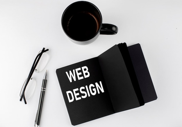 web-design-written-text-small-black-notebook-with-coffee-pen-glasess-white-background-blackwhite-style_376538-1674